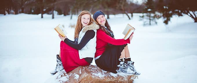 two girls reading feel good books in winter snow
