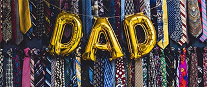 balloons spelling dad on background of ties