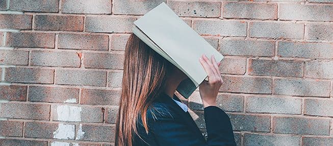 High school student with a book over her face.