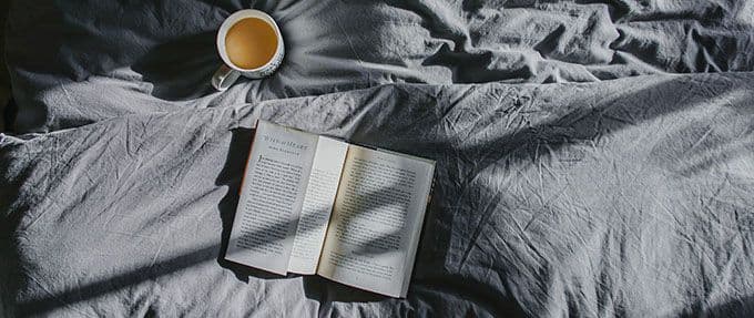 book on bed with coffee