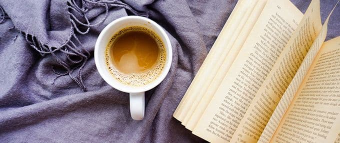 historical fiction book and espresso on purple scarf