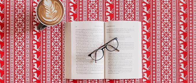 open book with glasses and coffee on a reindeer printed background