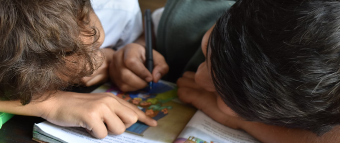 two boys reading and annotating a children's book