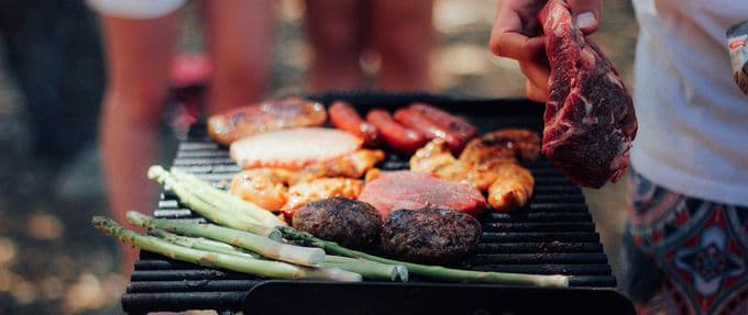 person grilling meat and vegetables