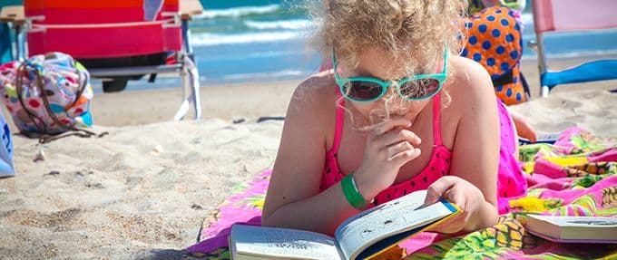 kid reading mystery book on beach